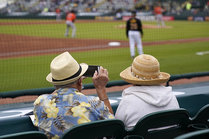 In this Monday, March 22, 2021 photo, two older adults socially distanced, watch a spring training exhibition baseball game between the Pittsburgh Pirates and the Baltimore Orioles in Bradenton, Fla. Spring has arrived with sunshine and warmer temperatures, and many vaccinated seniors are emerging from COVID-19-imposed hibernation. (Gene J. Puskar/AP, File)