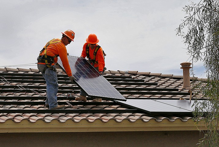In this July 28, 2015, file photo, electricians, Adam Hall, right, and Steven Gabert install solar panels on a roof for Arizona Public Service company in Goodyear, Ariz. As states across the U.S. West beef up their renewable energy mandates, a push to do so in Arizona has been met by fierce resistance from the Republican governor and GOP-dominated Legislature. (Matt York, AP File)