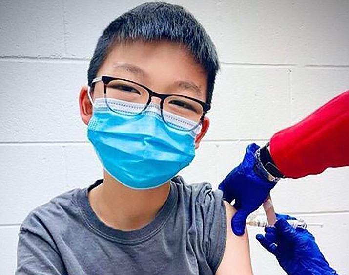 In this Dec. 22, 2020, photo, provided by Richard Chung, his son Caleb Chung receives the first dose of Pfizer coronavirus vaccine or placebo as a trial participant for kids ages 12-15, at Duke University Health System in Durham, N.C. Pfizer says its COVID-19 vaccine is safe and strongly protective in kids as young as 12. The announcement Wednesday, March 31, 2021, marks a step toward possibly beginning shots in this age group before the next school year. (Richard Chung via AP)