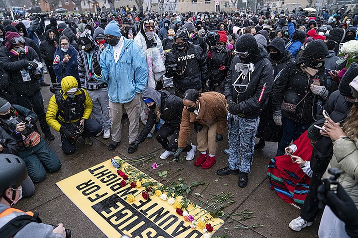 Flowers are placed on a banner as demonstrators gather outside the Brooklyn Center Police Department on Tuesday, April 13, 2021, to protest the shooting death of Daunte Wright on Sunday during a traffic stop in Brooklyn Center, Minn. (John Minchillo/AP)