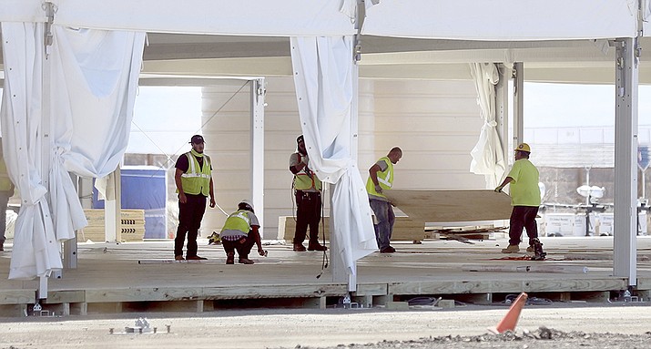 Crews work on tent-like structures constructed by U.S. Customs and Border Protection on the Southside of Tucson, Ariz., Tuesday, April 13, 2021. County officials in southern Arizona have said the federal government will provide $2.1 million to cover the costs of supporting people who are crossing the U.S.-Mexico border to seek asylum. (Kelly Presnell/Arizona Daily Star via AP)