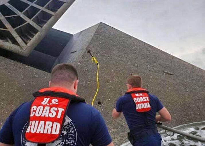 In this photo provided by the U.S. Coast Guard, Coast Guard Station Grand Isle 45-foot Response Boat-medium boat crew members attempt to throw a hammer at the hull of the SeaCor Power. The crew was attempting to make contact with potential survivors inside the vessel. . The Seacor Power, an oil industry vessel, flipped over Tuesday, April 13, 2021 in a microburst of dangerous wind and high seas. (U.S. Coast Guard via AP)