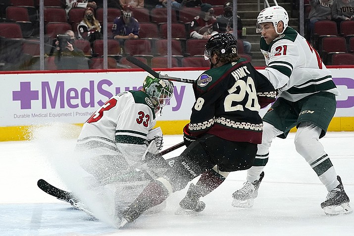 Minnesota Wild goaltender Cam Talbot (33) makes a save on a shot from Arizona Coyotes left wing Dryden Hunt (28) as Wild defenseman Carson Soucy (21) applies pressure during the first period of an NHL hockey game Monday, April 19, 2021, in Glendale, Ariz. (Ross D. Franklin/AP)