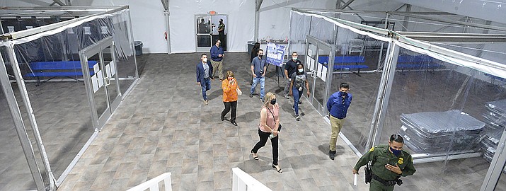 People touring the U.S. Border Patrol Yuma Sector, soft-sided processing facility, look at the pods inside one of four living areas at the facility during an open house, Tuesday, April 20, 2021, in Yuma, Ariz., in which the public was invited to see how the USBP will handle detained illegal immigrants who are apprehended while crossing the border into the United States from Mexico. The facility includes a laundry facility; multipurpose shower and changing area; an intake and medical area; processing area; 15 private phone rooms; and the four living areas, each divided into eight pods. (Randy Hoeft/The Yuma Sun via AP)