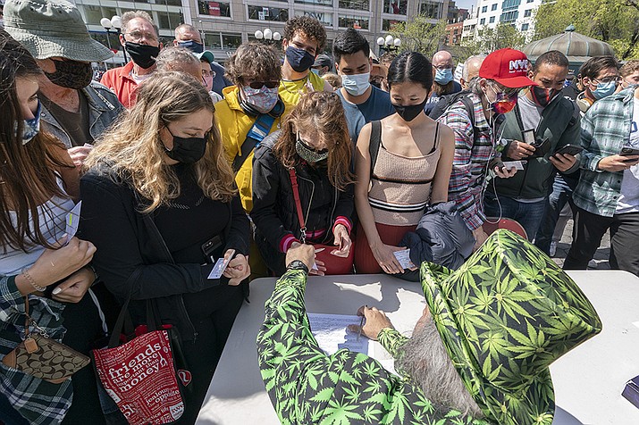 In this Tuesday, April 20, 2021, file photo, a man wearing a cannabis costume hands out marijuana cigarettes in New York during a "Joints for Jabs" event, where adults who showed their COVID-19 vaccination cards received a free joint. Free beer, pot and doughnuts. Savings bonds. A raffle ticket for a snowmobile. Places around the U.S. are offering incentives to try to energize the nation’s slowing vaccination drive and get reluctant Americans to roll up their sleeves. (Mark Lennihan, AP File)