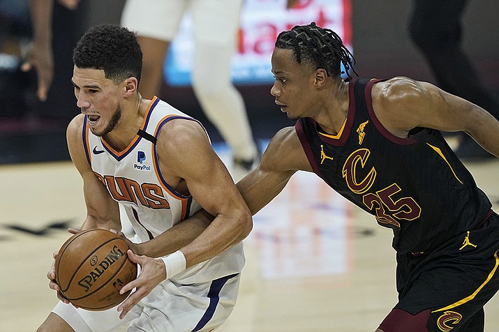 Phoenix Suns' Devin Booker, left, drives past Cleveland Cavaliers' Isaac Okoro in the first half of an NBA basketball game, Tuesday, May 4, 2021, in Cleveland. ( Tony Dejak/AP)