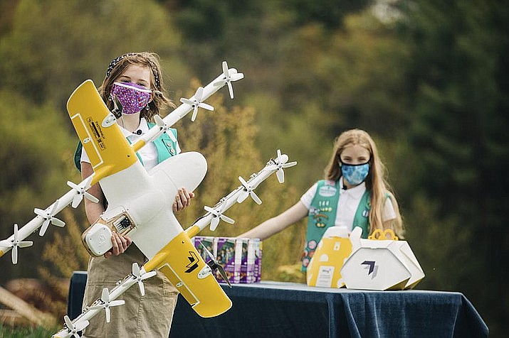 Girl Scouts Alice, right, and Gracie pose with a Wing delivery drone in Christiansburg, Va. The company is testing drone delivery of Girl Scout cookies in the area. (Sam Dean/ Wing LLC via AP)