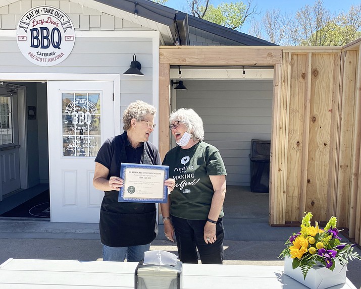 Lisa Lucidi (left) of Lucy Dee’s BBQ is recognized by Finding and Making the Good with flowers from Allan’s Flowers and a donation from El Gato Azul for her contributions to the community. (Prescott Woman Magazine/Courtesy)