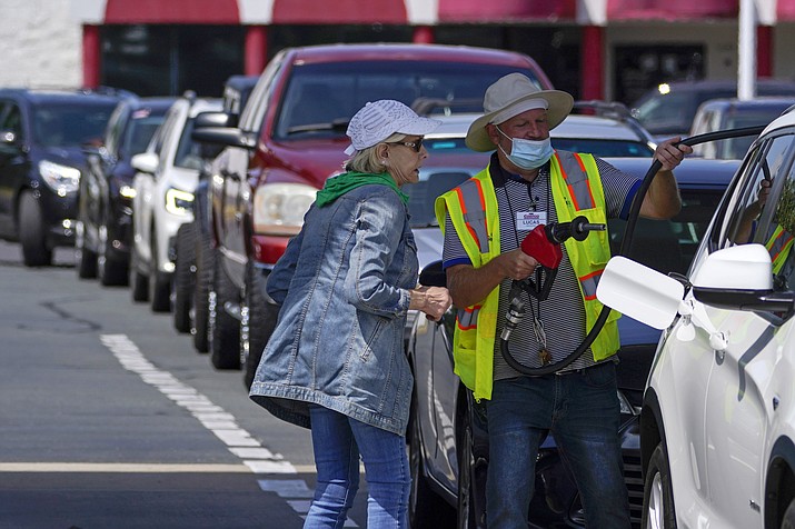 A customer helps pump gas at Costco, as others wait in line, on Tuesday, May 11, 2021, in Charlotte, N.C. Colonial Pipeline, which delivers about 45% of the fuel consumed on the East Coast, halted operations last week after revealing a cyberattack that it said had affected some of its systems. (Chris Carlson/AP)