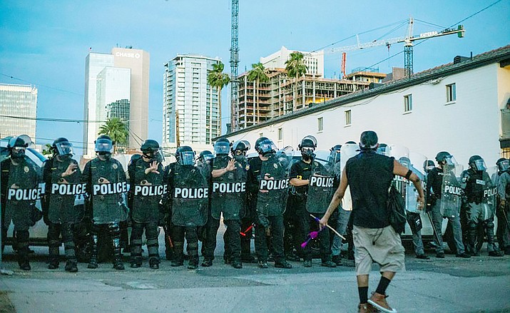 A protester approaches a line of police officers in downtown Phoenix on May 31, 2020, in one of several days of protests over the deaths of black men in police custody around the U.S. A statewide curfew was imposed that night. (Photo by Blake Benard/Special to Cronkite News)