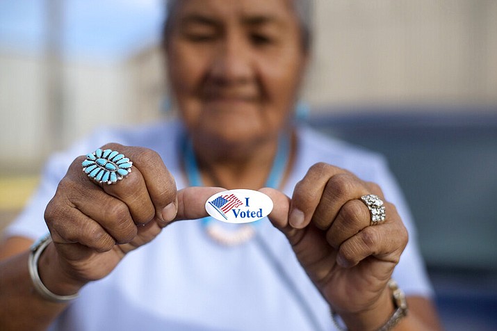 In this Aug. 28, 2018, file photo, Mildred James of Sanders, Arizona, shows off her "I Voted" sticker as she awaits election results in Window Rock, Arizona, on the Navajo Nation. The tribe says bills recently signed into Arizona law would make voting more difficult than it already is on the vast reservation. (AP Photo/Cayla Nimmo, File)