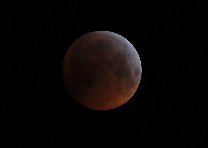 In this Monday, Jan. 21, 2019 file photo, the Earth’s shadow falls across the full moon seen above Brighton, southeast England. The first total lunar eclipse in more than two years coincides with a supermoon this week for a cosmic show. This super “blood” moon will be visible Wednesday, May 26, 2021 across the Pacific _ offering the best viewing _ as well as the western half of North America, bottom of South America and eastern Asia. (Alastair Grant/AP, file)