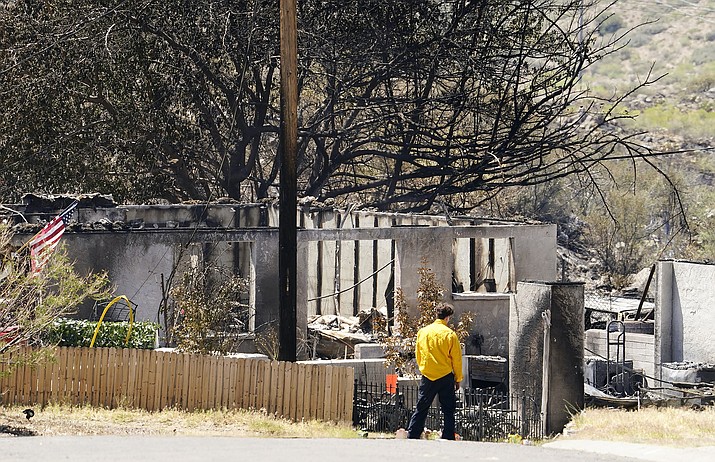 A person surveys the remains of a charred home from the Spur Fire that burned 150 acres and destroyed 13 homes and other structures Friday, May 28, 2021 in Bagdad, Ariz. (Rob Schumacher/The Arizona Republic via AP, Pool)
