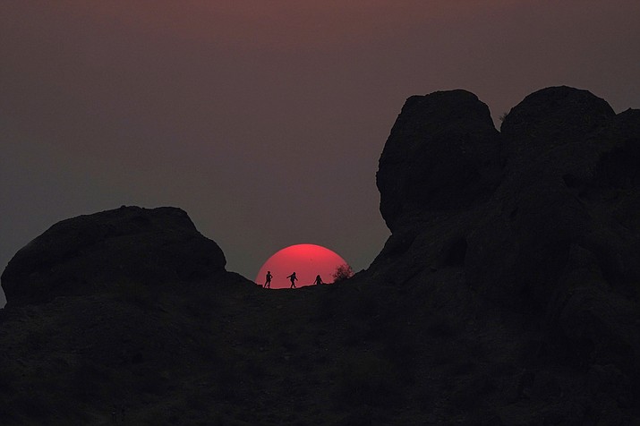 Hikers pause to watch the sunset at Papago Park during a heatwave where temperatures reached 115-degrees Tuesday, June 15, 2021, in Phoenix. (Ross D. Franklin/AP, file)
