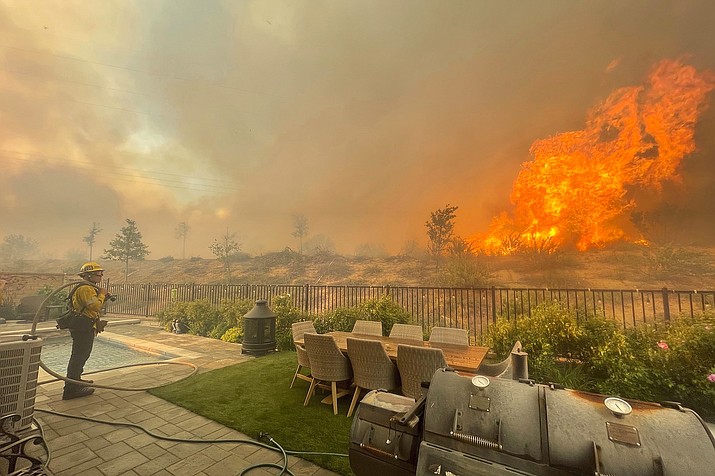 A firefighter prepares to battle the North Fire from a backyard on Via Patina, in Santa Clarita, California in April. U.S. wildfire officials, expecting increased fire activity and more demand for firefighters, have raised the national preparedness to level 4, unusual for June. The National Interagency Fire Center raised the level June 22, 2021, and says it's the second earliest it reached that level on the 1-5 scale since 1990. (Emily Alvarenga//The Santa Clarita Valley Signal via AP, File)