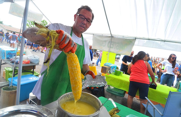 Andy Weiss dips corn for customers at the Corn Fest in Camp Verde on Saturday, July 17, 2021. (Vyto Starinskas/Independent)