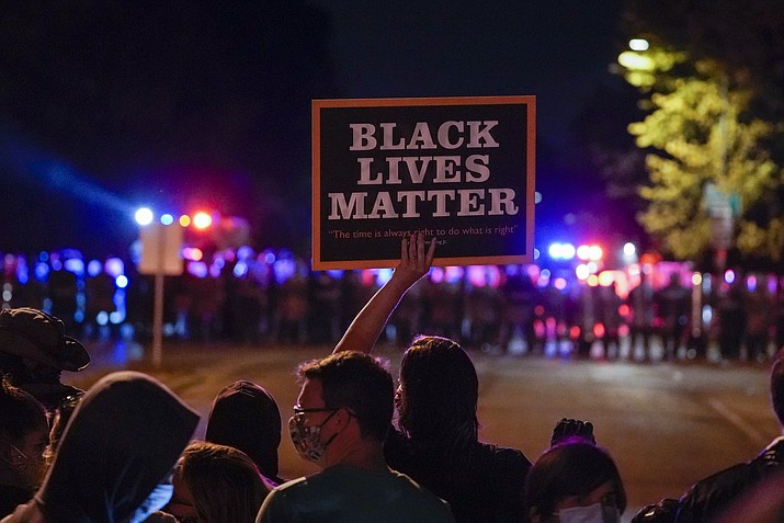 In this Oct. 2020, photo, protesters and police line up in Wauwatosa, Wis., in the case against Wauwatosa Police Officer Joseph Mensah for the Feb. 2 fatal shooting of 17-year-old Alvin Cole at Mayfair Mall. A Wisconsin judge was set to announce Wednesday, July 28, 2021, whether he will invoke a rarely used process to charge Mensah in the 2016 slaying of a Black man who was sitting in a parked car. (Morry Gash/AP, File)