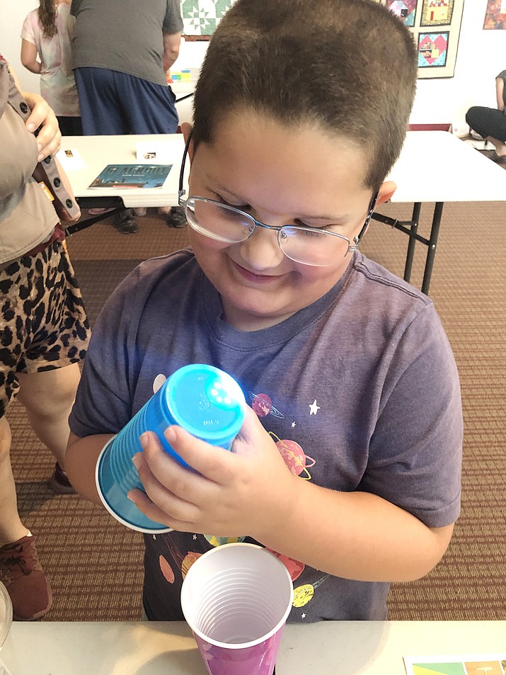 Virgil Fairchild, 6, plays with a flashlight learning how to make shapes with experiments set up at the Chino Valley Public Library on Friday, July 23, 2021. (Corrina Sisk-Casson/Review)