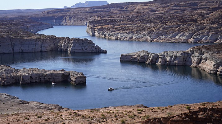 A boat cruises along Lake Powell July 31, 2021, near Page, Ariz. The National Park Service said the family rented a ski boat, toured the lake and stopped in a cove near Warm Creek Bay on Thursday, Aug. 5. Two children went swimming without life jackets and one began to struggle. The father jumped from the boat and got the children on the vessel but went underwater. With the help of three other boats the father was found at least 10 minutes after he went under water, officials said. CPR was unsuccessful. (AP file photo)