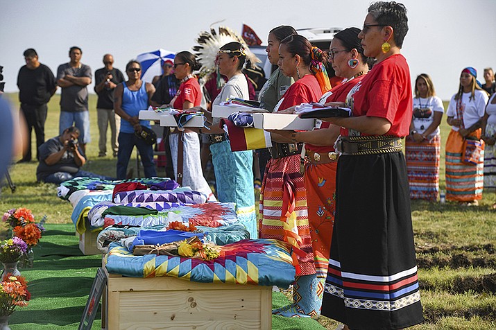 Members of the tribal color guard hold an American flag, a prayer flag and the Rosebud Sioux tribal flag for relatives of the Rosebud Sioux children, who were returned home 142 years after their deaths, at the Rosebud Sioux Tribe Veterans Cemetery in White River, S.D. The American Bar Association’s policymaking body voted Aug. 9, in favor of a resolution supporting the U.S. Interior Department as it works to uncover the troubled legacy of federal boarding schools that sought to assimilate Indigenous youth into white society. (Erin Bormett/The Argus Leader via AP, File)