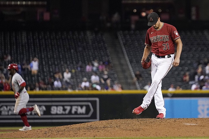 Arizona Diamondbacks relief pitcher Caleb Smith (31) kicks the dirt on the mound after giving up a home run to Philadelphia Phillies’ Odubel Herrera, left, during the eighth inning of a game Wednesday, Aug. 18, 2021, in Phoenix. (Ross D. Franklin/AP)