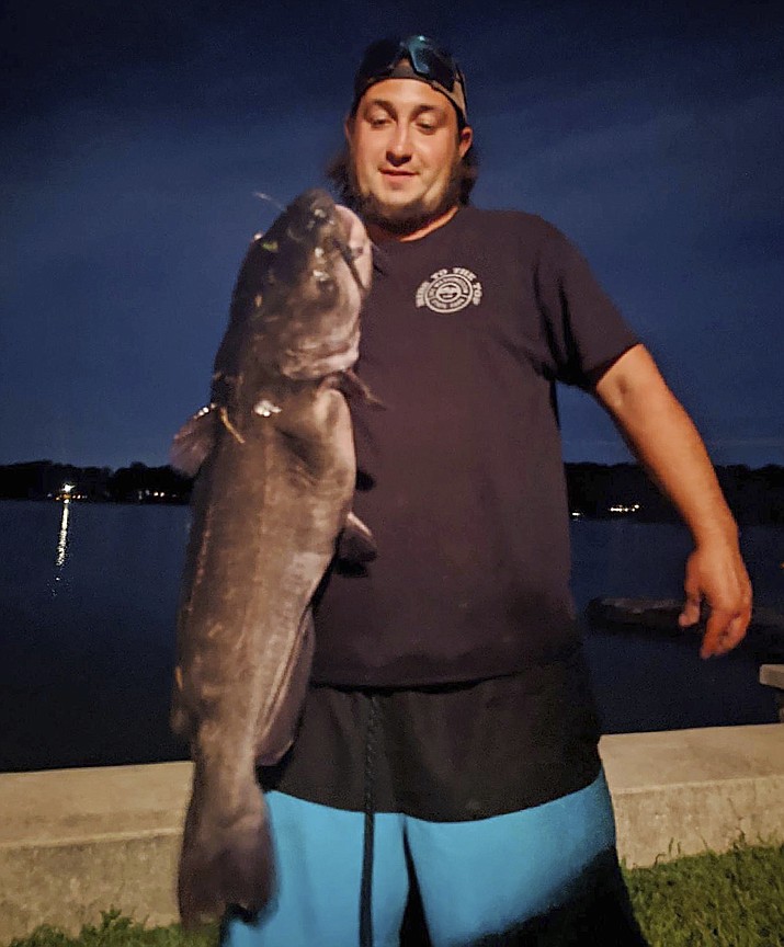 Ben Tomkunas holds a catfish he caught in Coventry, Conn., on Aug. 21, 2021, that has smashed a state record and could also be a world record for the species — though the evidence now has been eaten. (Chris Braga via AP)