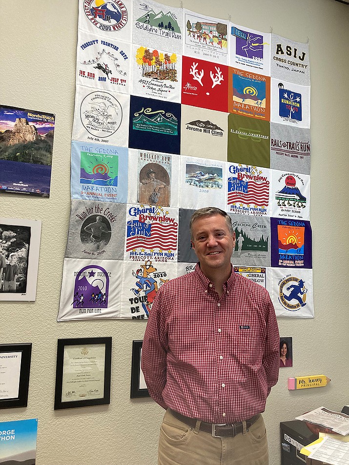 Prescott Unified School District Director of Human Resources Clark Tenney stands in front of a quilt his wife, Sonya, made out of T-shirts from some of the more than 100 road races he has participated in over the years. (Nanci Hutson/Courier)