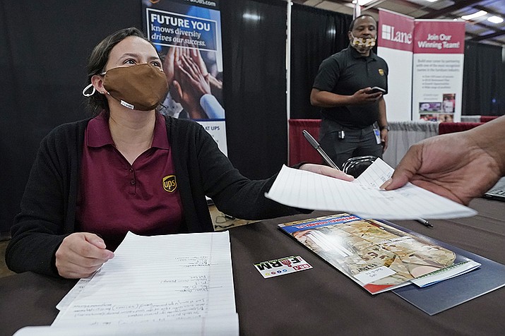 Ariel Jones, a United Parcel Service human resources intern, hands an applicant an information sheet, while the human resources specialist for the company, Mareno Moore, right, monitors the interaction during the Lee County Area Job Fair in Tupelo, Miss., Tuesday, Oct. 12, 2021. (Rogelio V. Solis/AP)