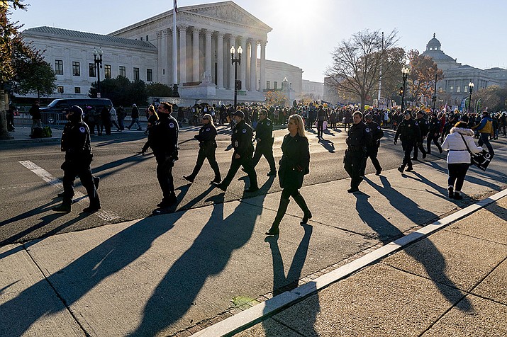 Police officers walk along the road where abortion rights advocates and anti-abortion protesters demonstrate in front of the U.S. Supreme Court, Wednesday, Dec. 1, 2021, in Washington, as the court hears arguments in a case from Mississippi, where a 2018 law would ban abortions after 15 weeks of pregnancy, well before viability. (Andrew Harnik/AP)