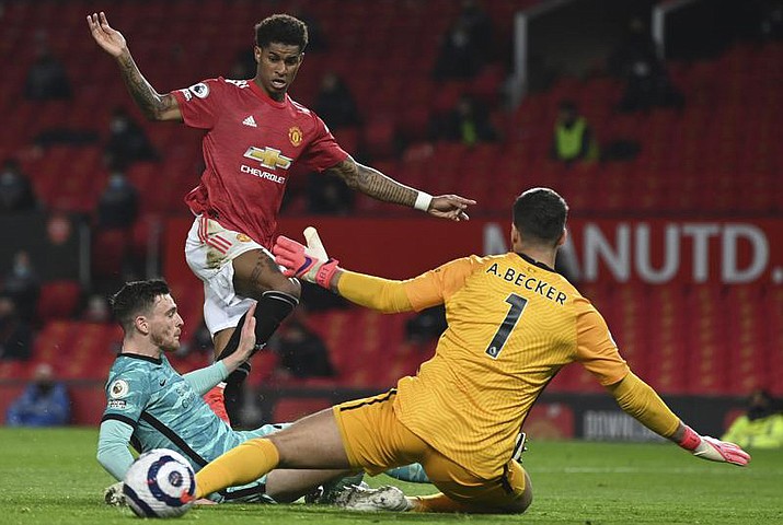 Manchester United's Marcus Rashford, top, scores his side's second goal during the English Premier League soccer match between Manchester United and Liverpool at the Old Trafford Stadium in Manchester, England, Thursday, May 13, 2021. New Jersey gambling regulators have fined two sports betting companies for mistakenly allowing 86 gamblers from New Jersey to place bets on whether Rashford would score a goal in the game, after the game had already ended and Rashford had in fact scored. (Michael Regan/Pool Photo via AP, File)