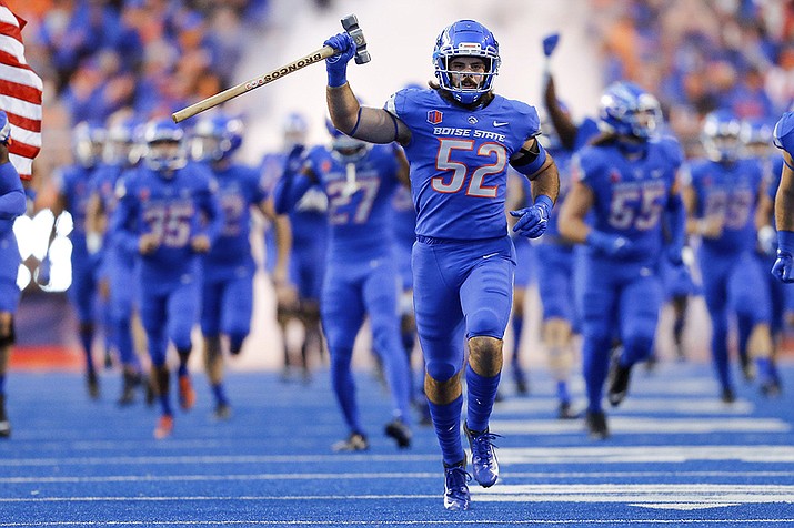 Boise State linebacker DJ Schramm (52), carrying the Dan Paul Hammer, leads Boise State onto the field before an NCAA college football game against Oklahoma State on Sept. 18, 2021, in Boise, Idaho. The Arizona Bowl was canceled on Monday night, Dec. 27, after Boise State pulled out and shut down all team activities due to COVID-19 issues within the program. (Steve Conner, AP File)