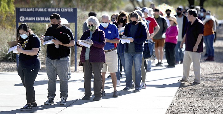 Hundreds of people fill out paperwork while waiting to get free COVID test kits at the Pima County Health Department Abrams Public Health Center in Tucson Jan. 4, 2022. The line for the kits stretched around all four sides of the building from the start of the afternoon's distribution. (Kelly Presnell/Arizona Daily Star via AP)