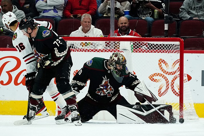 Arizona Coyotes goaltender Karel Vejmelka, right, makes a save as Coyotes center Travis Boyd (72) and Chicago Blackhawks left wing Jujhar Khaira battle for position during the first period of a game Thursday, Jan. 6, 2022, in Glendale. (Ross D. Franklin/AP)