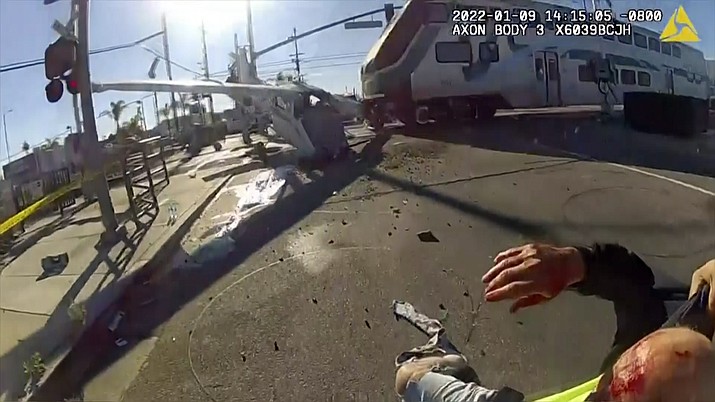 In this screen grab from a body cam video provided by the Los Angeles Police Department, a commuter train crashes with a plane which had just taken off from nearby Whiteman Airport Sunday, Jan. 9, 2021 in Pacoima, Calif. Los Angeles police officers pulled an injured pilot from the wreckage of a small plane that crash landed on railroad tracks just moments before a commuter train smashed into the aircraft over the weekend. (Los Angeles Police Department via AP)