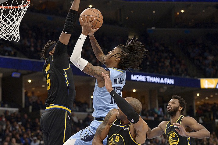 Memphis Grizzlies guard Ja Morant (12) shoots against Golden State Warriors center Kevon Looney (5), and forwards Andre Iguodala (9) and Andrew Wiggins (22) in the second half of an NBA basketball game Tuesday, Jan. 11, 2022, in Memphis, Tenn. (Brandon Dill/AP)