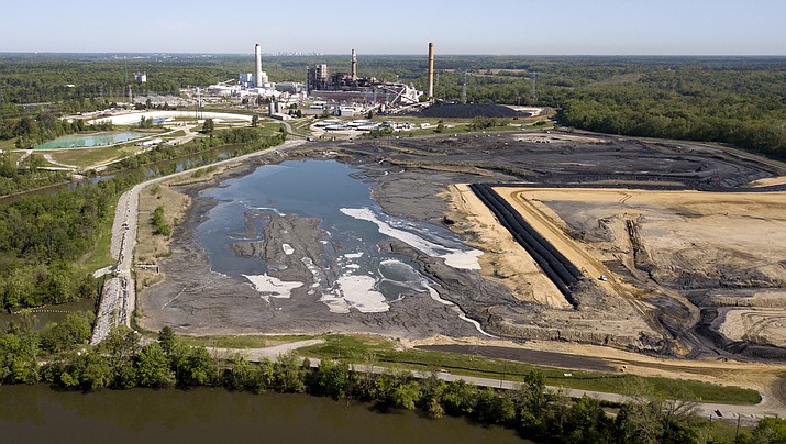 In this May 1, 2018, photo, the Richmond, Va., city skyline is seen in the horizon behind the coal ash ponds along the James River near Dominion Energy's Chesterfield Power Station in Chester, Va. In the first first major action to address toxic wastewater from coal-burning power plants, the Environmental Protection Agency is denying requests by three Midwest power plants to extend operations of leaking or otherwise dangerous coal ash storage ponds. (Steve Helber/AP, File)