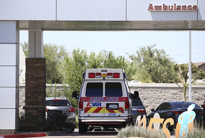 In this June 10, 2020, photo, an ambulance is parked at Arizona General Hospital in Laveen. Arizona is continuing to see slight downward trends with coronavirus hospitalizations as officials find more related deaths. Arizona is committing millions of dollars and asking the federal government for extra help as hospitals face a growing strain from rising COVID-19 caseloads and warn they are nearing their limits. (Ross D. Franklin/AP, File)