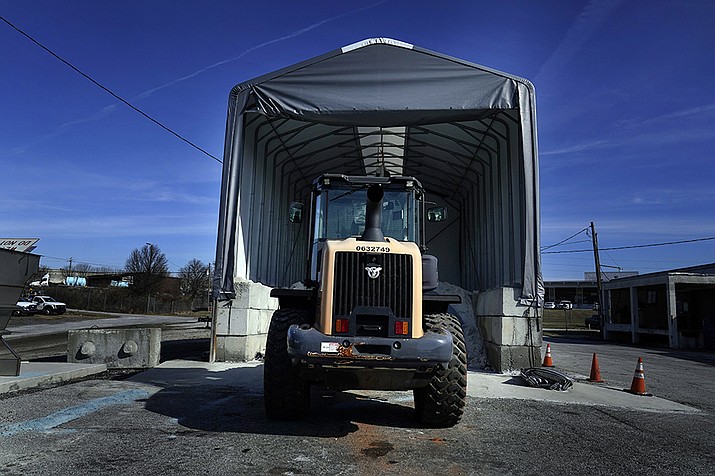 A tractor sits in front of a pile of salt used to create a brine that will help clear road of ice and snow ahead of a winter storm at the GDOT's Maintenance Activities Unit location on Friday, Jan. 14, 2022, in Forest Park, Ga. A winter storm is headed south that could effect much of Georgia through Sunday. (Brynn Anderson/AP)