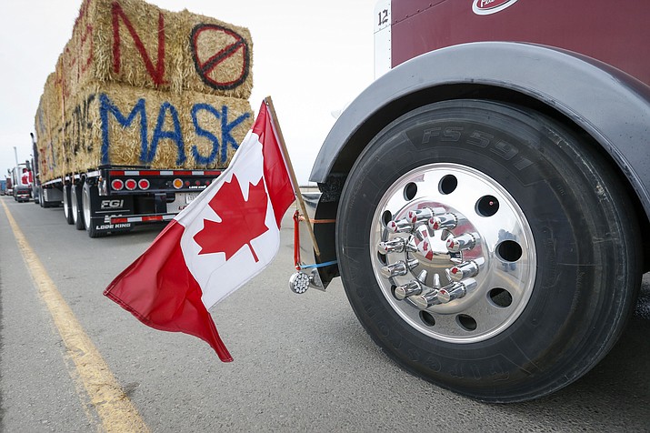 The Canadian flag is reflected in a wheel hub as anti-COVID-19 vaccine mandate demonstrators gather as a truck convoy blocks the highway at the busy U.S. border crossing in Coutts, Alberta, Canada, Monday, Jan. 31, 2022. Thousands of antivaccine protesters descended on Canada’s capital of Ottawa in frigid temperatures to protest vaccine mandates, masks and restrictions over the weekend and some remain, blocking traffic around Parliament Hill in what has been the biggest pandemic protest in the country to date. (Jeff McIntosh/The Canadian Press via AP)