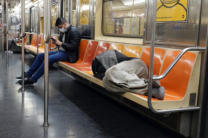 A man sleeps on subway train seats, in New York, on April 14, 2021. New York Mayor Eric Adams is announcing a plan to boost safety in the city's sprawling subway network and try to stop homeless people from sleeping on trains or living in stations. (Richard Drew/AP, File)