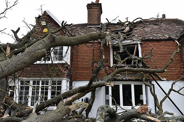 Sven Good, 23, looks out from his bedroom window at the damage caused to the family home a day after a 400-year-old oak tree in the garden was uprooted by Storm Eunice, in Stondon Massey, near Brentwood, Essex, England, Saturday Feb. 19, 2022. Crews cleared fallen trees and worked to restore power to about 400,000 people in Britain as Western Europe cleaned up Saturday after one of the most damaging storms in years. At least 12 people were killed, many by falling trees, in Ireland, Britain, Belgium, the Netherlands and Germany. Named Storm Eunice by the British and Irish weather services, and Storm Zeynep in Germany, Friday's storm was the second to hit the region in a week. (Nicholas.T.Ansell/PA via AP)