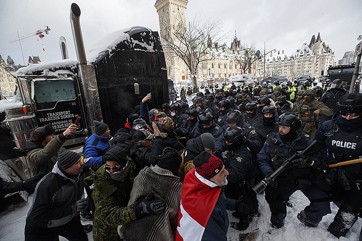 Police move in to clear downtown Ottawa near Parliament Hill of protesters on Saturday, Feb. 19, 2022. Police resumed pushing back protesters on Saturday after arresting more than 100 and towing away vehicles in Canada’s besieged capital, and scores of trucks left under the pressure, raising authorities’ hopes for an end to the three-week protest against the country’s COVID-19 restrictions. (Cole Burston /The Canadian Press via AP)
