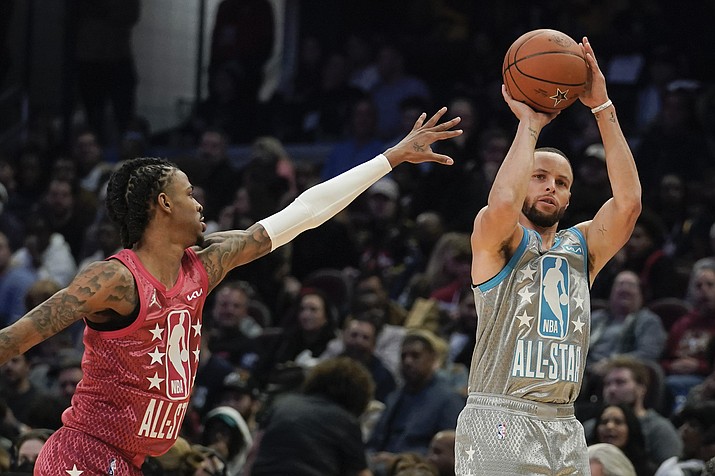 Golden State Warriors' Stephen Curry, right, shoots for three as Memphis Grizzlies' Ja Morant defends during the second half of the NBA All-Star game, Sunday, Feb. 20, 2022, in Cleveland. (Charles Krupa/AP)
