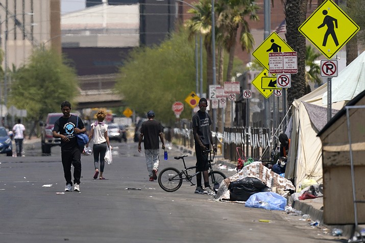 Pedestrians walk along the street next to a homeless encampment as temperatures continued to soar past 115-degrees Thursday, June 17, 2021, in Phoenix. (Ross D. Franklin/AP)