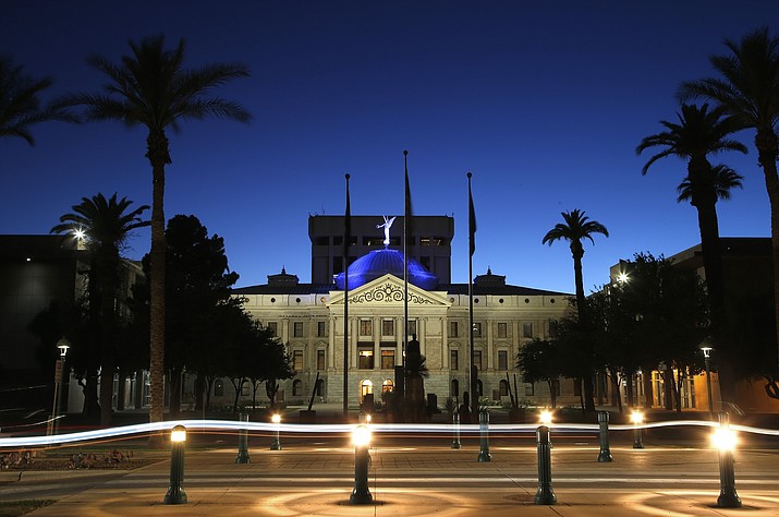 The blur of car lights zip past the Arizona Capitol as the dome is illuminated on April 15, 2020, in Phoenix. A proposal that would bar any government agency in Arizona contracting with a firm that refuses to do business with a firearms company got strong support from majority Republicans on a state House committee but tough pushback from the banking industry. (Ross D. Franklin/AP, File)