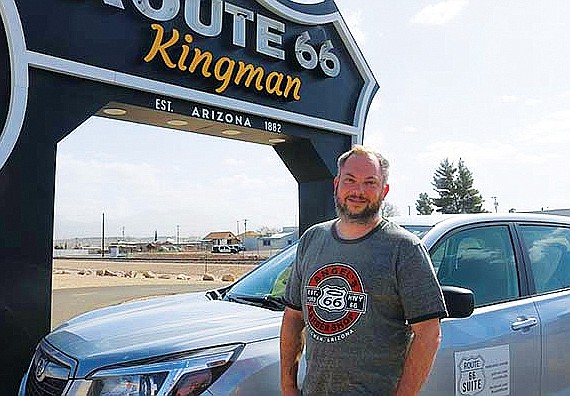 Music professor and composer Nolan Stolz poses beside the Route 66 Kingman sign outside the Powerhouse Visitor’s Center. (Photo by Travis Rains/Kingman Miner)