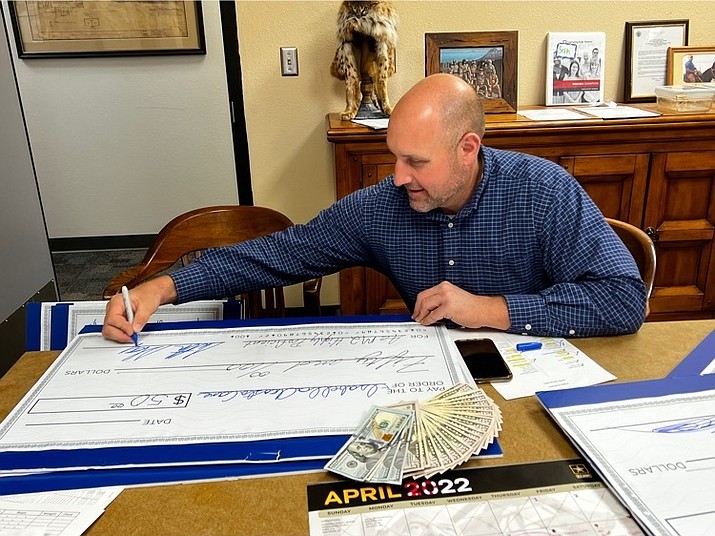Ash Fork Superintendent Seth Staples signs a check for a student who rated highly proficient on the AZ Merit test. APS donated $50 per high achieving student at the school, with a total of $1,600 donated to the students. (Photo/AFJUSD)