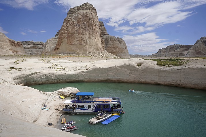 In this July 30, 2021, photo, a houseboat rests in a cove at Lake Powell near Page, Ariz. Federal water officials have announced that they will keep hundreds of billions of gallons of Colorado River water inside Lake Powell instead of letting it flow downstream to southwestern states and Mexico. U.S. Assistant Secretary of Water and Science Tanya Trujillo said Tuesday, May 3, 2022, that the move would allow the Glen Canyon Dam to continue producing hydropower while officials strategize how to operate the dam with a lower water elevation. (AP Photo/Rick Bowmer, File)