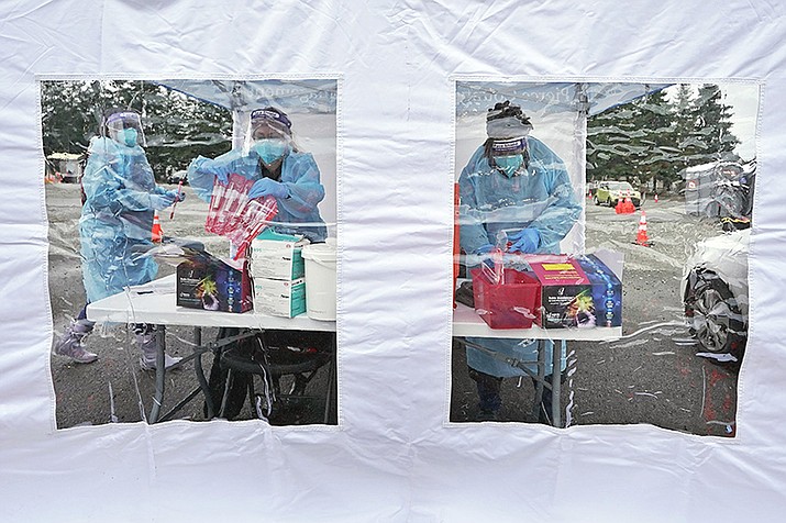 Workers at a drive-up COVID-19 testing clinic stand in a tent as they prepare PCR coronavirus tests, Jan. 4, 2022, in Puyallup, Wash., south of Seattle. Testing for COVID-19 has plummeted across the globe, dropping by 70 to 90% worldwide from the first to the second quarter of 2022, making it much tougher for scientists to track the course of the pandemic and spot new, worrisome viral mutants as they emerge and spread. (Ted S. Warren/AP)