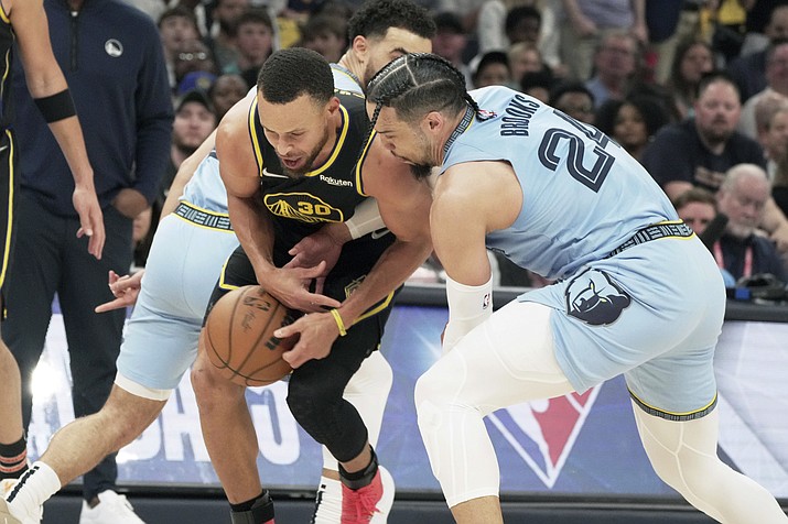 Memphis Grizzlies’ Dillon Brooks (24) and Golden State Warriors’ Stephen Curry (30) battle for the ball in the first half of Game 5 of a second-round playoff series Wednesday, May 11, 2022, in Memphis, Tenn. (Karen Pulfer Focht/AP)